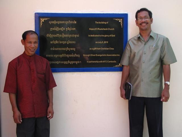 Pastor Vin and Barnabas Mam by the recognition plaque